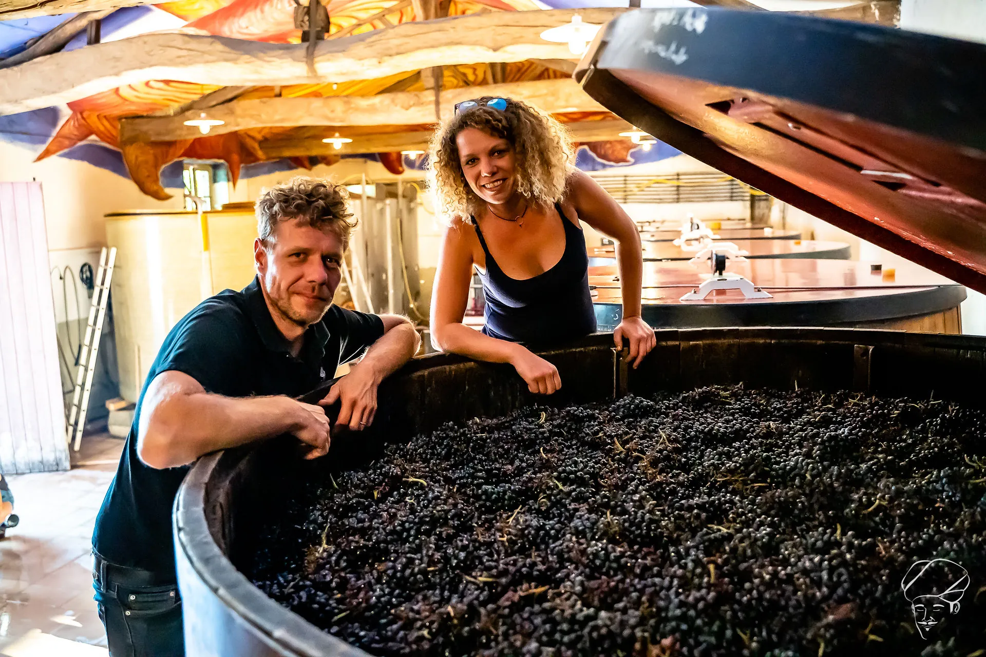 Mathieu et Camille Lapierre accoudés à une cuve en bois remplie de raisins